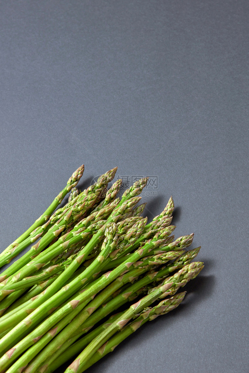 新鲜采摘的天然芦笋,用于灰色背景下准备纯素食品,并素食健康饮食灰色背景上的堆绿色机芦笋图片