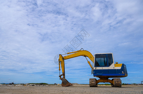 黄色装载机反铲堆干木屑与蓝天工厂里的工业图片
