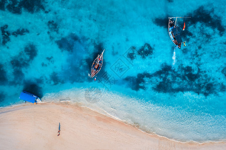 夏天日出时,清澈的蔚蓝的水中俯瞰渔船无人驾驶的船,蓝色的大海,沙滩,步行的人印度洋旅行带摩托艇的热带海景背景图片