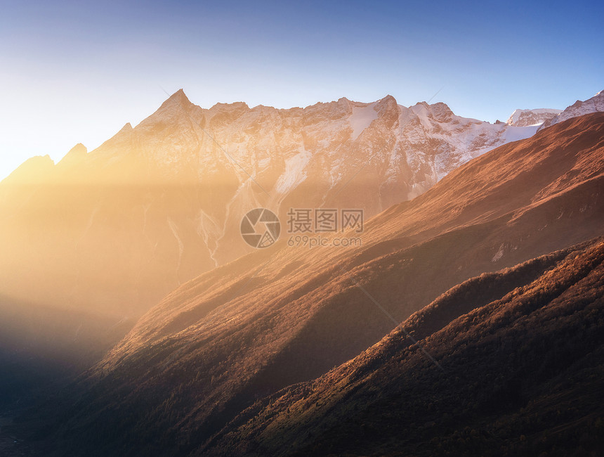 美丽的山脉雪峰阳光明媚的早晨尼泊尔日出时喜马拉雅山脉的轮廓五颜六色的景观,高岩石,蓝天金色的阳光神奇的喜马拉图片