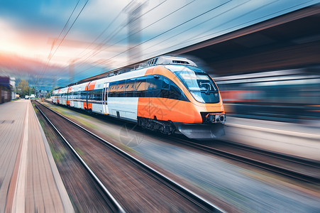 日落时火车站上的高速橙色列车运动现代城际客运列车铁路站台上运动模糊效应工业欧洲的铁路运输高速橙色列车背景图片