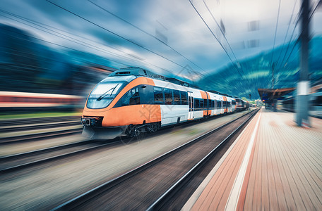 客运机车日落时火车站上的高速橙色列车运动现代城际客运列车铁路站台上运动模糊效应工业欧洲的铁路运输高速橙色列车背景