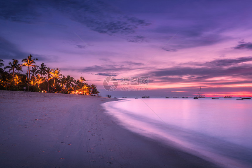 沙滩上棕榈树,夏天五颜六色的日落热带景观与海岸,模糊的水,棕榈,船游艇海洋,紫色的天空与云夜间异国他乡的非洲图片