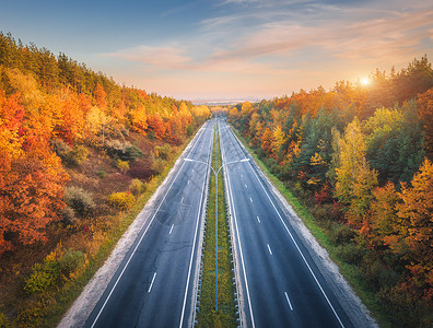 日落时美丽的秋林中沥青路的鸟瞰图五颜六色的景观与空的公路,树木与红色橙色的叶子,蓝天与阳光秋天巷道的顶部视图秋天背景图片