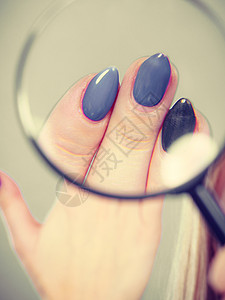 凝胶混合美甲金发女人看着她蓝色的长而漂亮的指甲女人放大镜看指甲图片