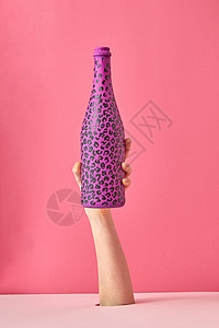 女人的手着粉红色背景上黑点的油漆瓶,涂粉红色背景上黑点的热粉黑点图片