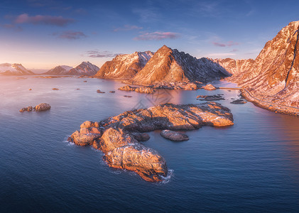 空中俯瞰大海中的岩石,雪山,日落时挪威洛福滕岛旅行冬季景观与小岛屿水,悬崖波浪看背景图片