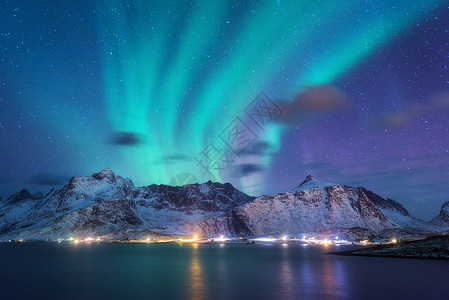 海上极光北极光海上,雪山城市灯光夜间挪威洛福滕岛的北极光紫色的星空极地的灯光冬季景观与极光反射水中背景