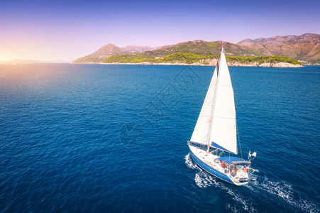 顶部比利茨基美丽的白色帆船蔚蓝的海洋明亮的阳光明媚的夏天晚上的鸟瞰克罗地亚的亚得里亚海景观游艇,山,透明的碧水,日落的天空背景