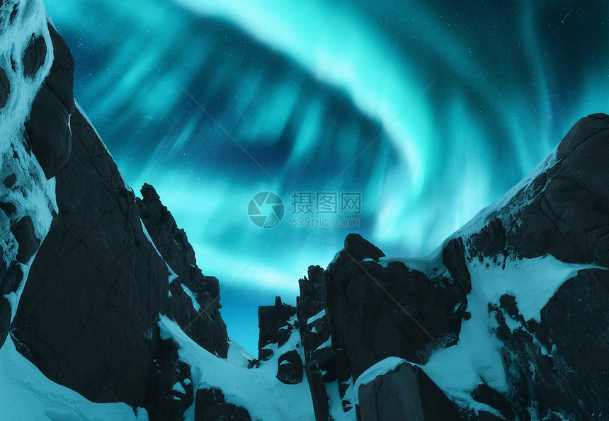 北极光覆盖挪威洛福腾群岛的雪山上冬天的北极光夜间景观与极地灯光,雪岩星空极光美丽的自然图片