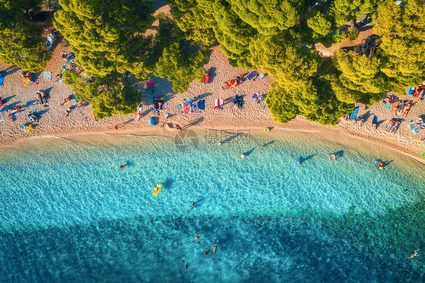 鸟瞰沙滩,五颜六色的雨伞,游泳的人,清澈的海湾,透明的蓝色水绿树日落夏天克罗地亚,亚得里亚海旅行的风景海图片