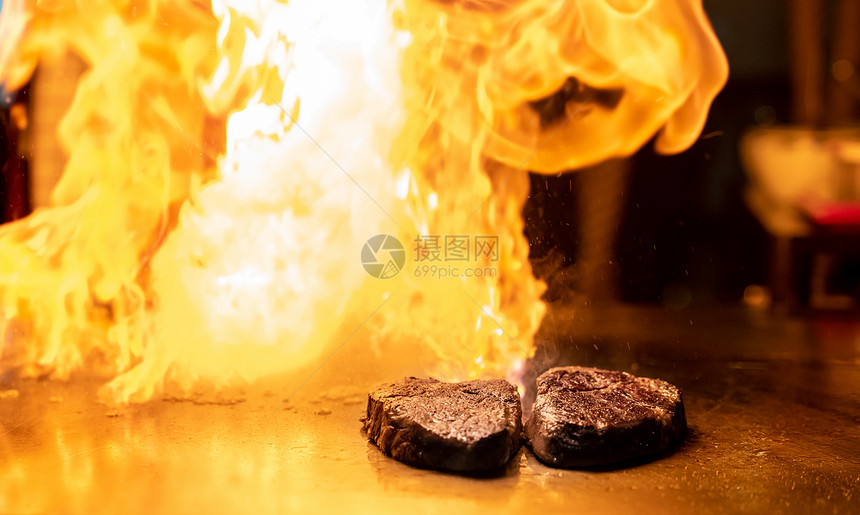 烤牛肉铁板烧食谱日本烤牛肉烹饪锅用刮刀与火焰背景图片
