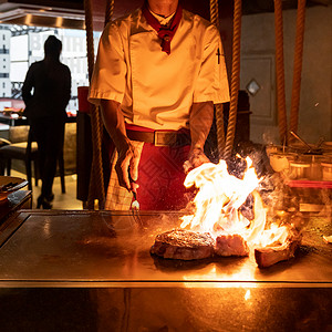 烤牛肉铁板烧食谱日本烤牛肉战斧牛排烹饪锅用刮刀与火焰背景背景图片