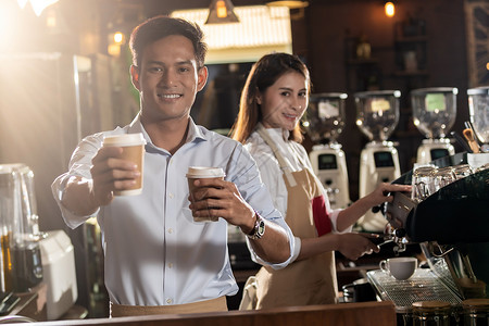 亚洲咖啡师的肖像,走咖啡杯,并咖啡馆为客户服务,其他咖啡师后台工作图片