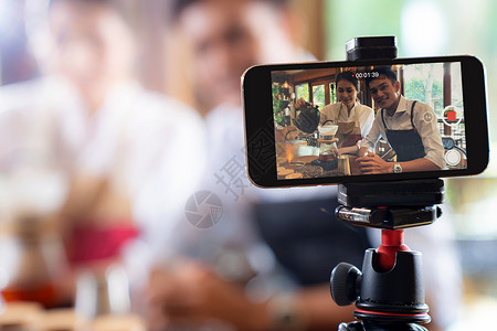 视频线轻的亚洲业主企业家Vlog回顾咖啡馆咖啡店,并生活社交媒体上,咖啡馆用智能手机进行线营销用于启动小企业营销消费主义背景