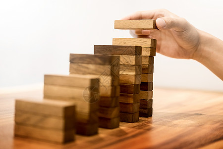 人手把安排堆叠以促进发展的木制块作为阶梯增长概念和成功计划背景图片