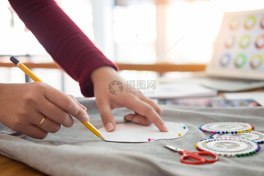 女时装设计师在工作室与草画一起工作在裁缝桌上选择粗制进度图片
