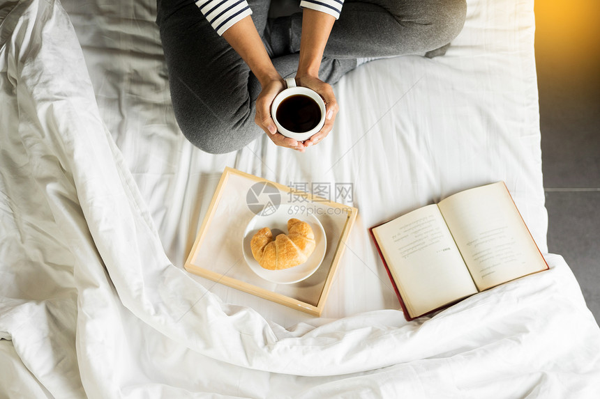 妇女早上在床上喝咖啡读书图片