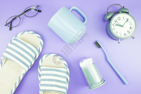 紫色桌面与物品蓝紫和概念下的牙刷眼镜毛巾和拖鞋顶视图背景
