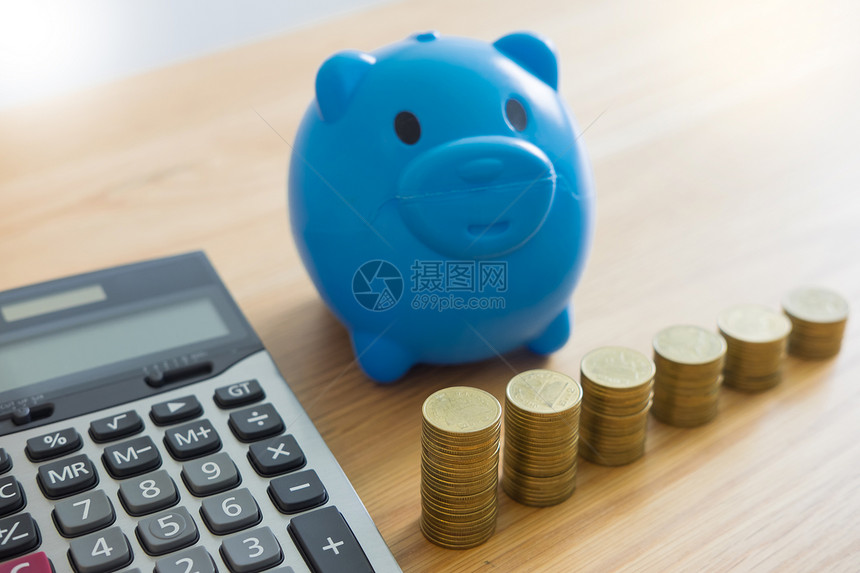 小猪银行和堆叠的硬币塔上面有工作桌的图表数据投资增长金节省的概念图片
