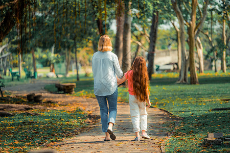 孩子和母亲在公园里牵手散步图片