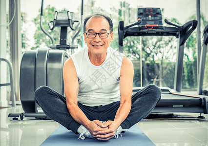 在健身房的垫子上做瑜伽的老人图片