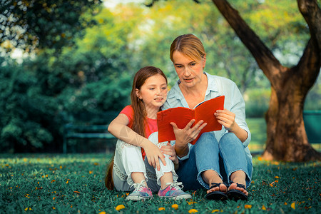 户外公园中母女在草地看书幸福的高清图片素材