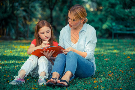 户外公园中母女在草地看书支持高清图片素材