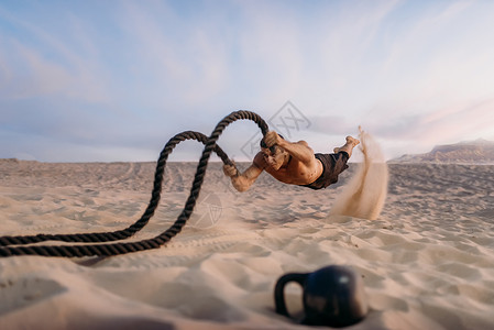 男子在沙漠用战绳进行锻炼运动图片