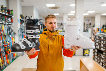 冬季在体育商店购买滑雪靴的男顾客图片