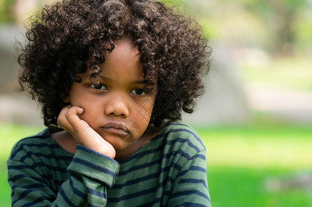 坐在公园里的非洲小孩情绪消极的男孩儿童麻烦的概念图片