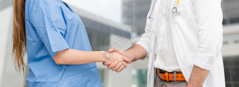 医院生与另一名保健人员握手协同工作背景图片