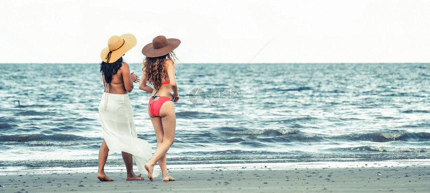 比基尼的快乐妇女一起在暑假的热带沙滩上晒太阳图片