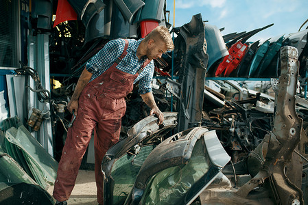 男修理工在汽车垃圾场选择零部件图片