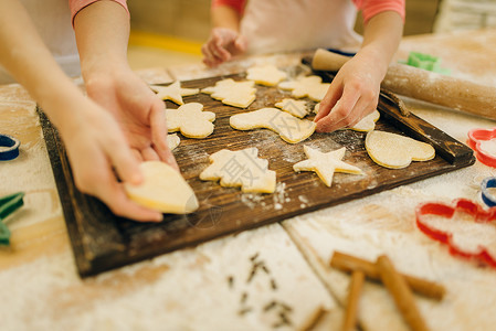 两个小女厨师在厨房木板上撒面粉做饼干背景