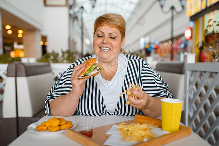在快餐厅吃高卡路里食品的胖女人高清图片