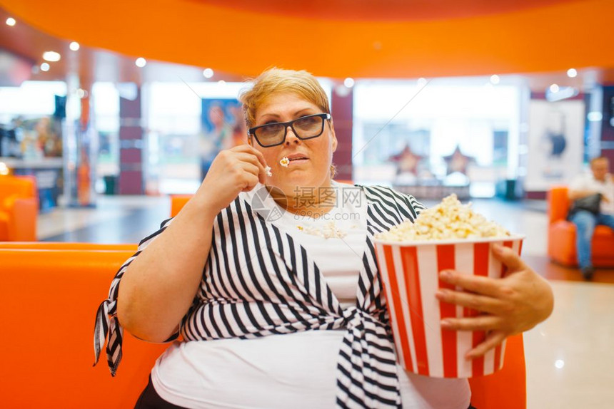 在电影厅吃爆米花不健康垃圾食品超重女在商场肥胖问题图片