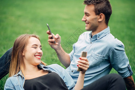 夫妻躺在草地上使用智能手机通信高清图片素材