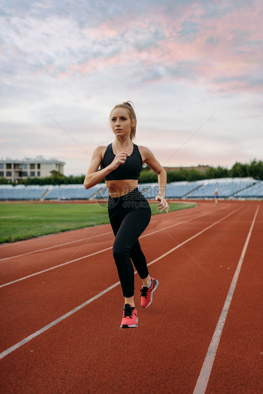 女运动员穿着运动服在体育场慢跑图片