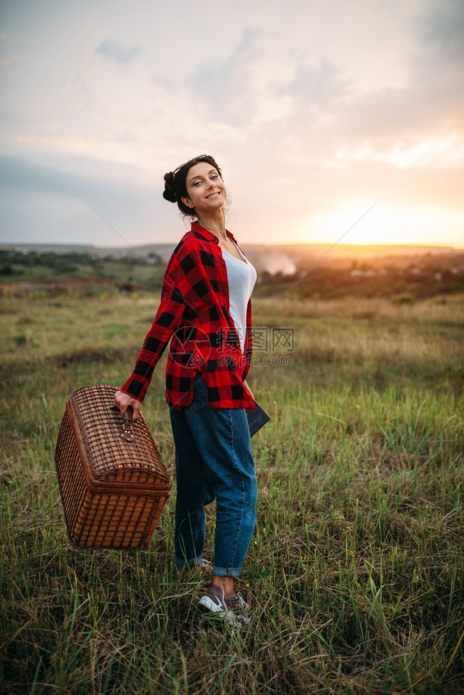 提着篮子的女人在草地上行走图片