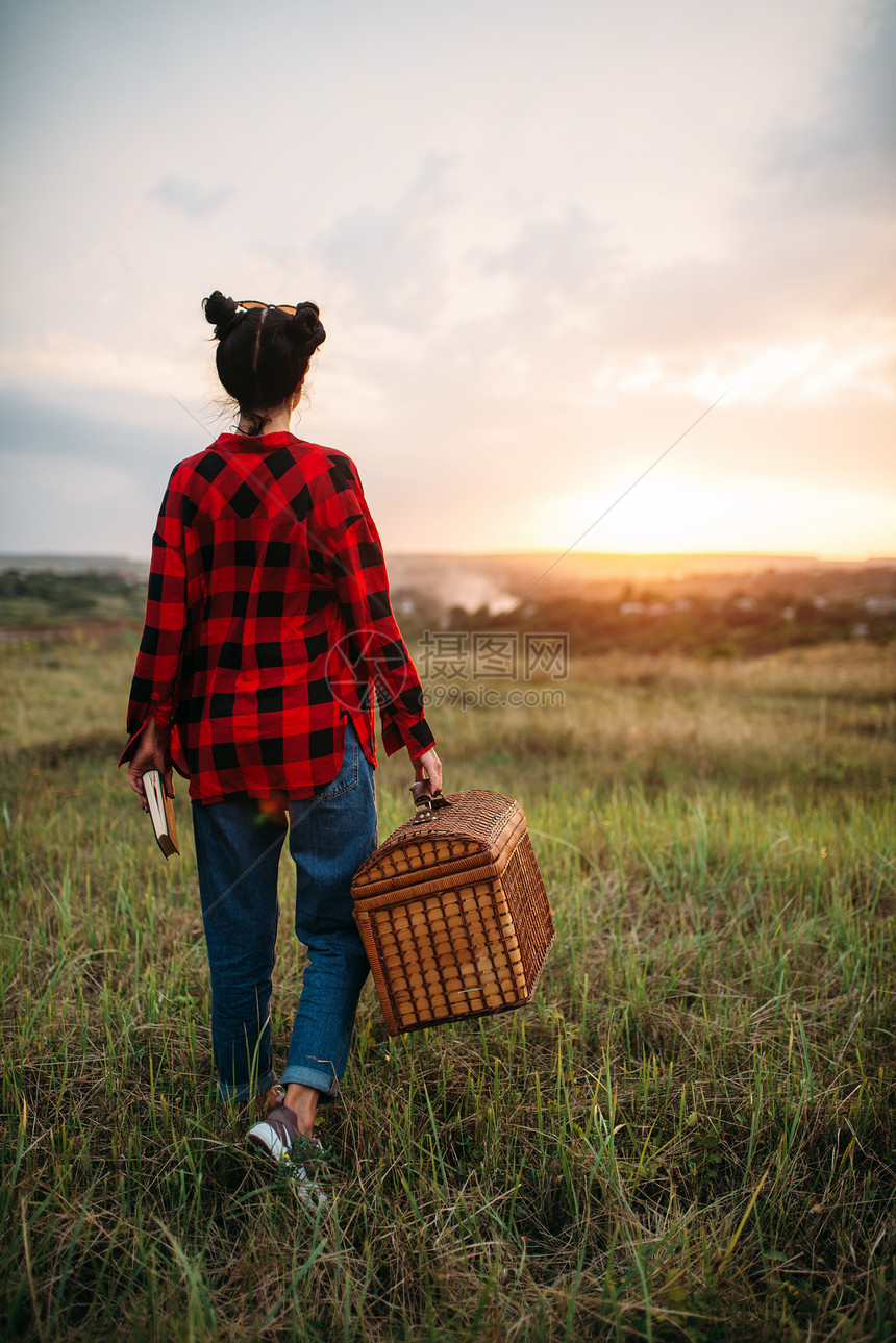 提着篮子的女人在草地上行走图片