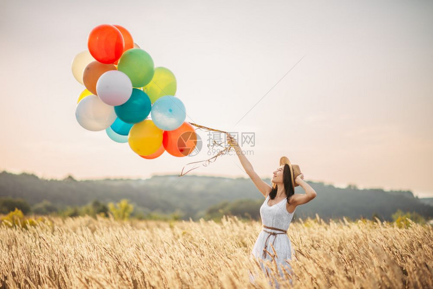 麦田漂亮女人抓着彩色气球图片