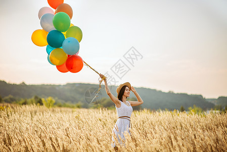 漂亮女孩在麦田里手拉气球背景图片
