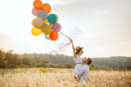 夏天情侣在田里的手拉热气球背景图片