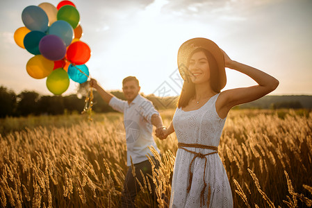 休闲美丽的妻子和丈夫在夏日草原上行走户外的高清图片素材