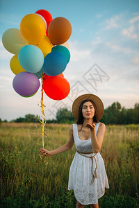 绿地上美女牵着气球发出一个吻图片