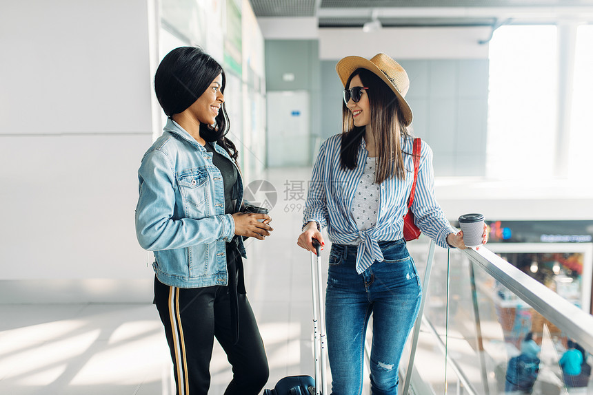 携带行李的女旅客在机场开心交谈图片