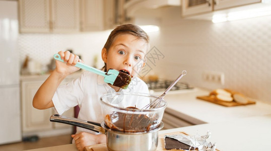 小孩在厨房做饭快乐的孩子准备甜点小孩在碗里吃巧克力图片