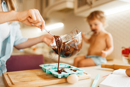 年轻妈妈和孩子准备融化巧克力做糕点高清图片