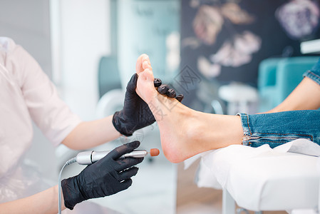 脚戴铁球戴着黑色手套的医生对顾客的脚做治疗背景